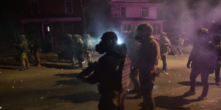 Federal law enforcement agents and police officers in riot gear walk amid smoke from crowd control devices after protests broke out following the shooting of a Venezuelan man by a Immigration and Customs Enforcement agent in Minneapolis, Minnesota, on Jan. 14, 2026.