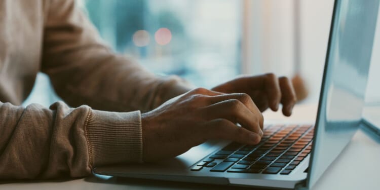 A man works on his laptop at an office desk.