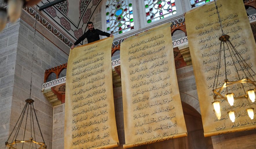 Rekar Zaman, son of Iraqi calligrapher Ali Zaman, holds one scroll of a massive handwritten manuscript of the Quran, Islam's holy book, at the Mihrimah sultan mosque, in Istanbul, Turkey, Wednesday, Jan. 14, 2026. Ali Zaman worked six years to write 302 double-sided scrolls to complete a giant Quran. (AP Photo/Francisco Seco)