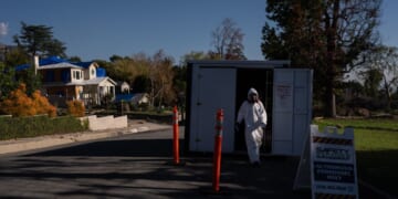 A worker in protective gear exits a storage container at a cleanup site on Dec. 3, 2025, months after the Eaton Fire, in Altadena, California.