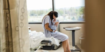 A Chinese mother lovingly holds her newborn baby in a hospital room.