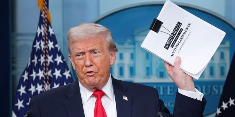 President Donald Trump displays a stack of papers labeled "The White House Accomplishments" as he arrives for a news briefing in the James S. Brady Press Briefing Room of the White House on Jan. 20, 2026, in Washington, D.C.