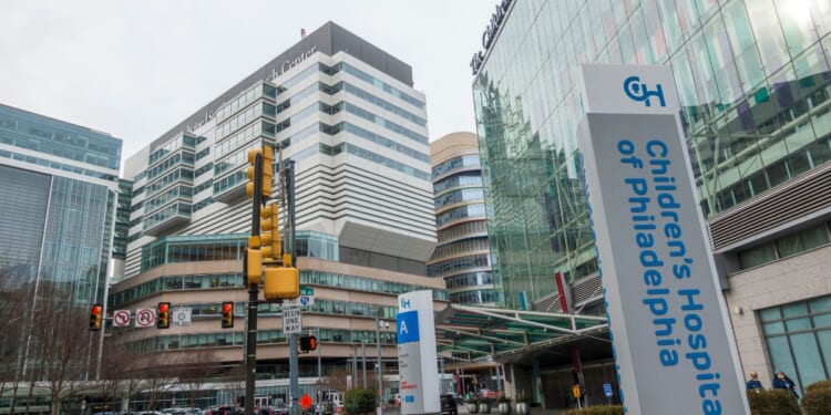 People walking on street in front of buildings of Hospital of the University of Pennsylvania and the Children's Hospital of Philadelphia.