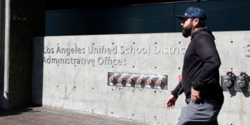 A person walks by a sign in front of the Los Angeles Unified School District headquarters Wednesday in Los Angeles, California. The FBI served search warrants at the Los Angeles Unified School District's headquarters and the home of Superintendent Alberto Carvalho as federal officials work on an ongoing investigation.