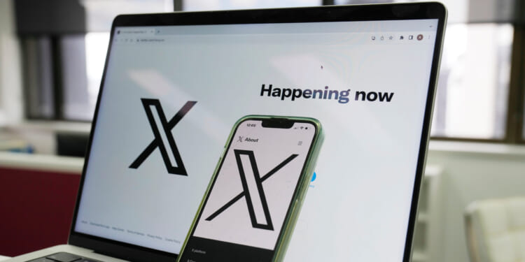 The opening page of X is displayed on a computer and phone on Oct. 16, 2023, in Sydney, Australia.