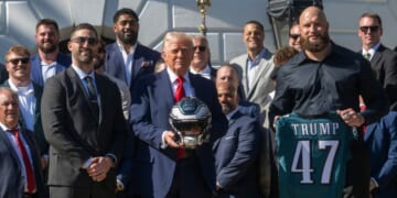 President Donald Trump holds up a helmet, flanked by Philadelphia Eagles tackle #65 Lane Johnson and Philadelphia Eagles head coach Nick Sirianni, as he hosts an event celebrating the Philadelphia Eagles, 2025 Super Bowl champions, at the White House on April 28, 2025, in Washington, D.C.