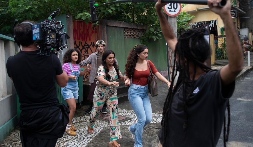 Actors Alana Cabral, behind left, Dira Paes, center, Sophie Charlotte, behind right, and Paulo Mendes, behind everyone, take part in the filming of the soap opera "Três Garças" at a TV Globo set in Rio de Janeiro, Thursday, March 12, 2026. (AP Photo/Bruna Prado)