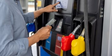 A man uses a credit card to pay for gas at a gas station.