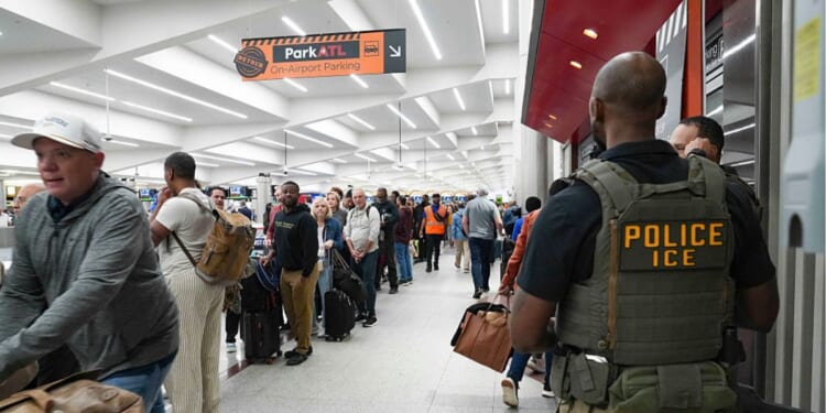 Ice agents look on Monday as travelers stand in long lines at Atlanta Hartsfield-Jackson International Airport in Atlanta, Georgia. The travel disruptions continue as hundreds of TSA agents quit or work without pay during a partial government shutdown. President Donald Trump said ICE agents will be deployed to U.S. airports, with border czar Tom Homan in charge of the effort.