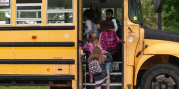 A group of elementary age children getting on a school bus.