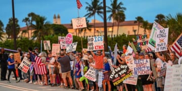 Protesters hold signs near President Donald Trump's Mar-a-Lago resort during the "No Kings" national day of protest, in Palm Beach, Florida, on May 28, 2026.