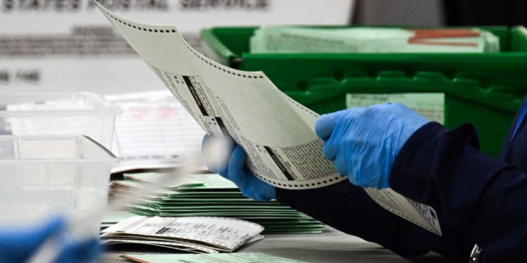 An election worker removes a ballot from an envelope to count and inspect the pages inside the Maricopa County Tabulation and Election Center on Election Day, Nov. 5, 2024, in Phoenix, Arizona.