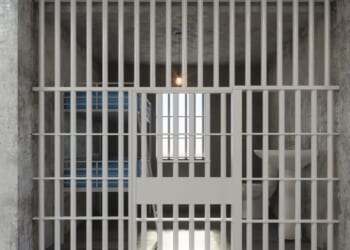 The front view of an empty prison cell with a bunkbed and sink.