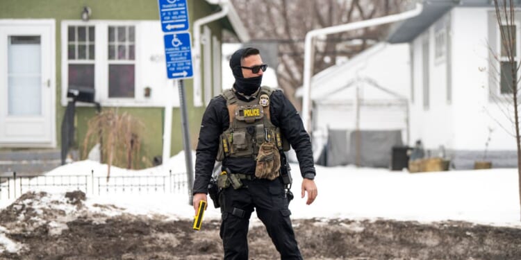 An ICE agent holds a taser as he stands watch after one of their vehicles got a flat tire on Penn Avenue on Feb. 5, 2026, in Minneapolis, Minnesota.
