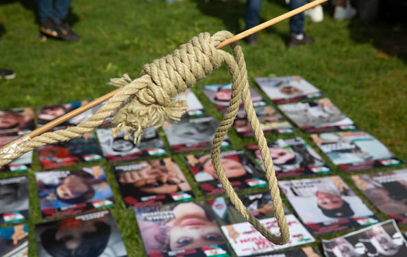 A woman holds a protest noose above photos of victims of Iranian executions on September 16, 2022.