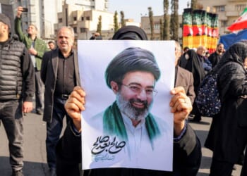 A woman poses with a picture of Iran's new Supreme Leader Ayatollah Mojtaba Khamenei during a rally in support of him Monday at Enghelab Square in central Tehran.