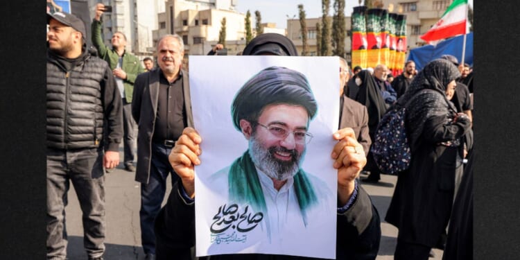 A woman poses with a picture of Iran's new Supreme Leader Ayatollah Mojtaba Khamenei during a rally in support of him Monday at Enghelab Square in central Tehran.