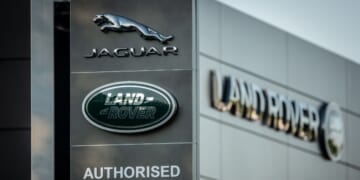 A Jaguar logo sits on a sign in the middle of the day outside a car dealership in Taunton, England on May 8, 2025.