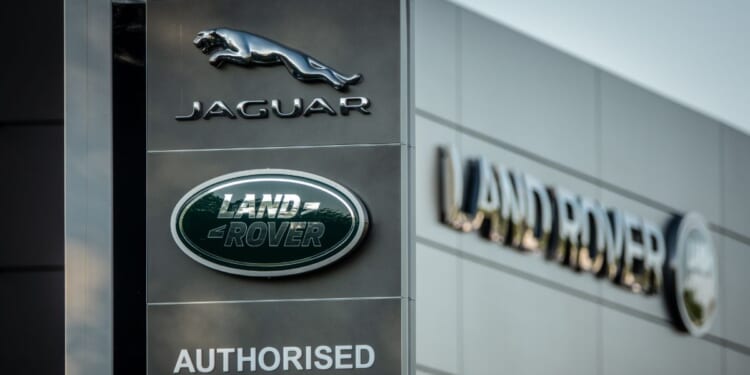 A Jaguar logo sits on a sign in the middle of the day outside a car dealership in Taunton, England on May 8, 2025.