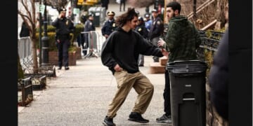 A left-wing activist is handed a homemade explosive device by a fellow activist before throwing it toward police during an anti-Islamic protest Saturday in front of Gracie Mansion, New York mayor Zohran Mamdani's official residence.