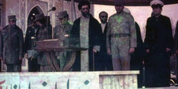 Iranian President Ali Khamenei surrounded by soldiers on stage in March of 1983.