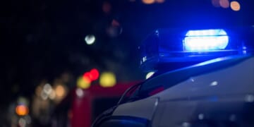 Lights flash on top of an emergency vehicle speeding down the road at night.