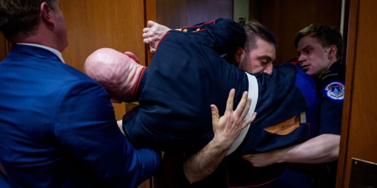 Protester Brian McGinnis is dragged out of a Senate Armed Services Subcommittee hearing on Capitol Hill and is stuck in a door on March 4, 2026.