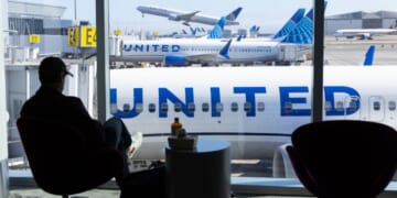 A man sits in an airport overlooking a United Airlines plane at San Francisco International Airport on Aug. 31, 2025.