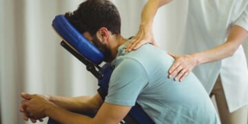 A therapist gives a back massage to a patient in a clinic.