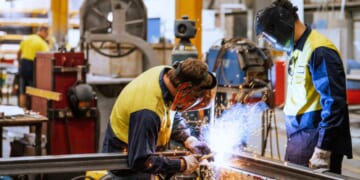 Workers wear protective gear as they use heavy machinery.