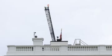 Workers are seen on top of a construction crane above the White House on April 28, 2026, in Washington, D.C.