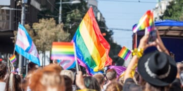 A picture of a crowd holding up LGBT flags during a gay pride parade.