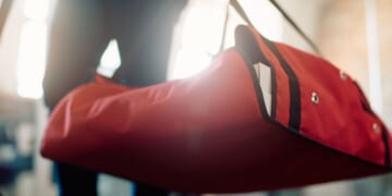 A close up of a delivery courier carrying pizza in a thermal bag.
