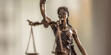 Lady Justice bronze statuette stands with the weight scales of Justice.