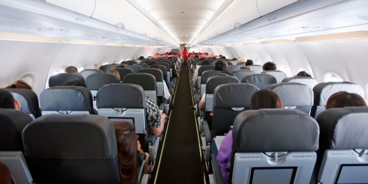 The inside of the cabin of a commercial airline flight with several passengers onboard.