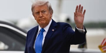 President Donald Trump waves after stepping off Air Force One at Joint Base Andrews upon returning from Florida Saturday.