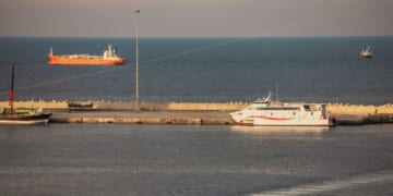 A police speed boat patrols the port as oil tankers and high speed crafts sit anchored at Muscat Anchorage near the Strait of Hormuz on March 30, 2026, in Muscat, Oman.