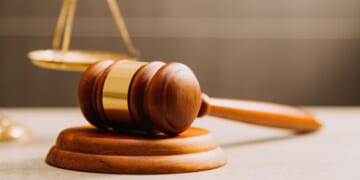 A gavel lays near a balancing scale.
