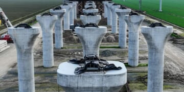 The unfinished high speed rail concrete columns stand in a vast green field.