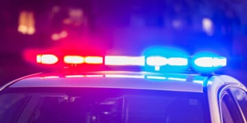 The roof of a police patrol car at night, with the blue and red lights flashing.