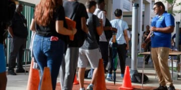 A Broward County gate supervisor examines students as they enter the campus for weapons on June 24, 2024.