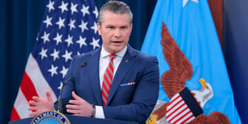 Secretary of War Pete Hegseth at a podium briefing reporters.